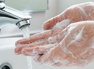 A person washing their soapy hands under running water