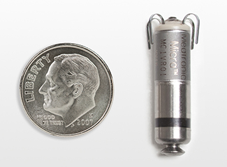 A coin positioned next to a compact metal device.